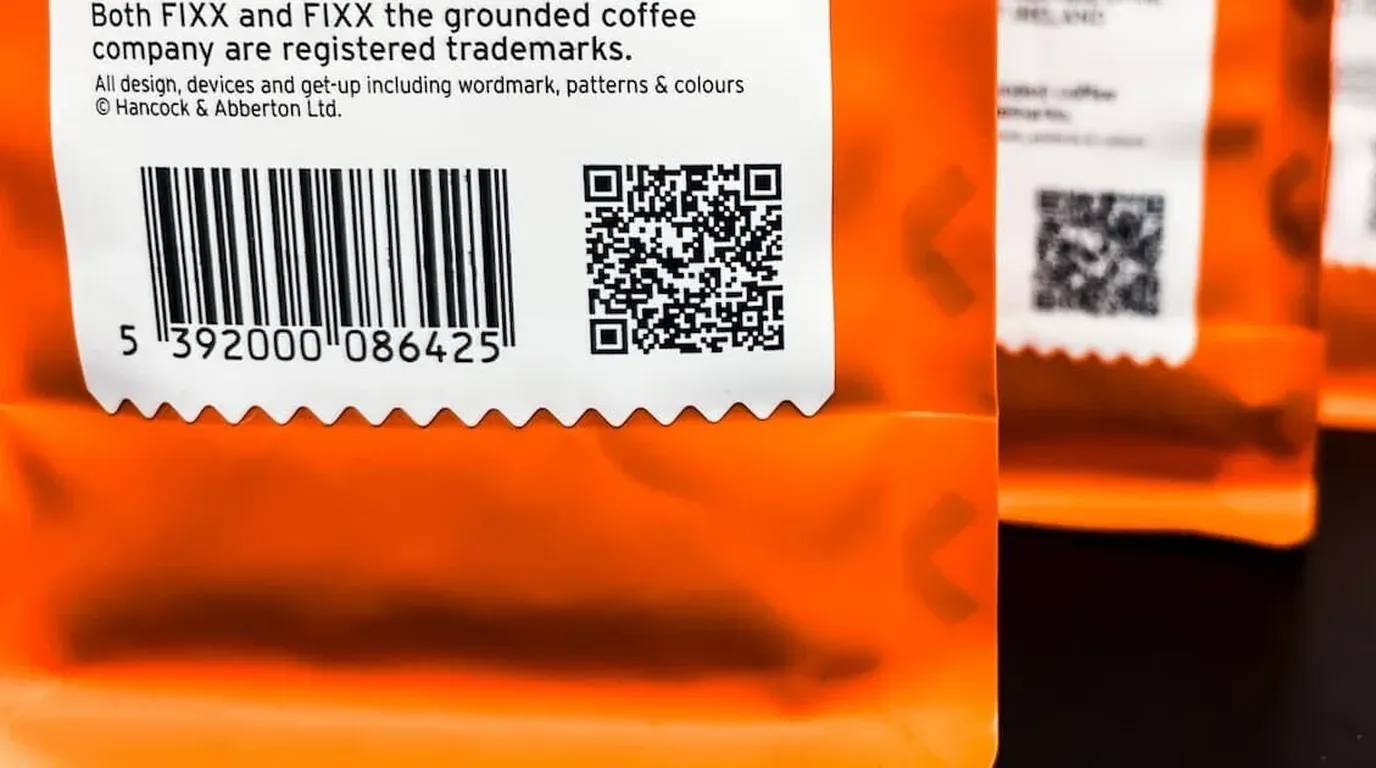 الرمز الشريطي ورمز QR جنبًا إلى جنب على كل كيس من FiXX لقطة مقرّبة للملصق الخلفي على كيس قهوة FiXX، يظهر فيها الرمز الشريطي EAN ورمز QR من Digital Link مطبوعين جنبًا إلى جنب